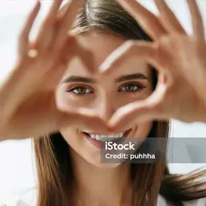 Woman making a heart sign with her hands and eyes peaking through it